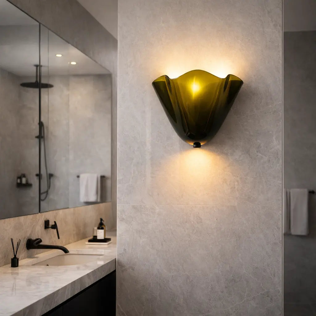 Olive green glass wall sconce mounted on textured bathroom wall