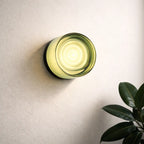 Green glass round wall sconce with warm ambient light